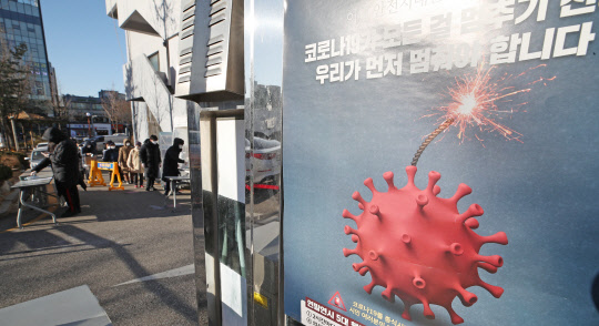 15일 오전 서울 강서구보건소에 마련된 코로나19 선별진료소에 부착된 코로나19 관련 포스터 뒤로 시민들이 문진표를 작성하고 있다.   연합뉴스